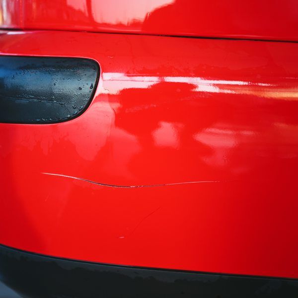 En rød bil med en ripe på støtfangeren